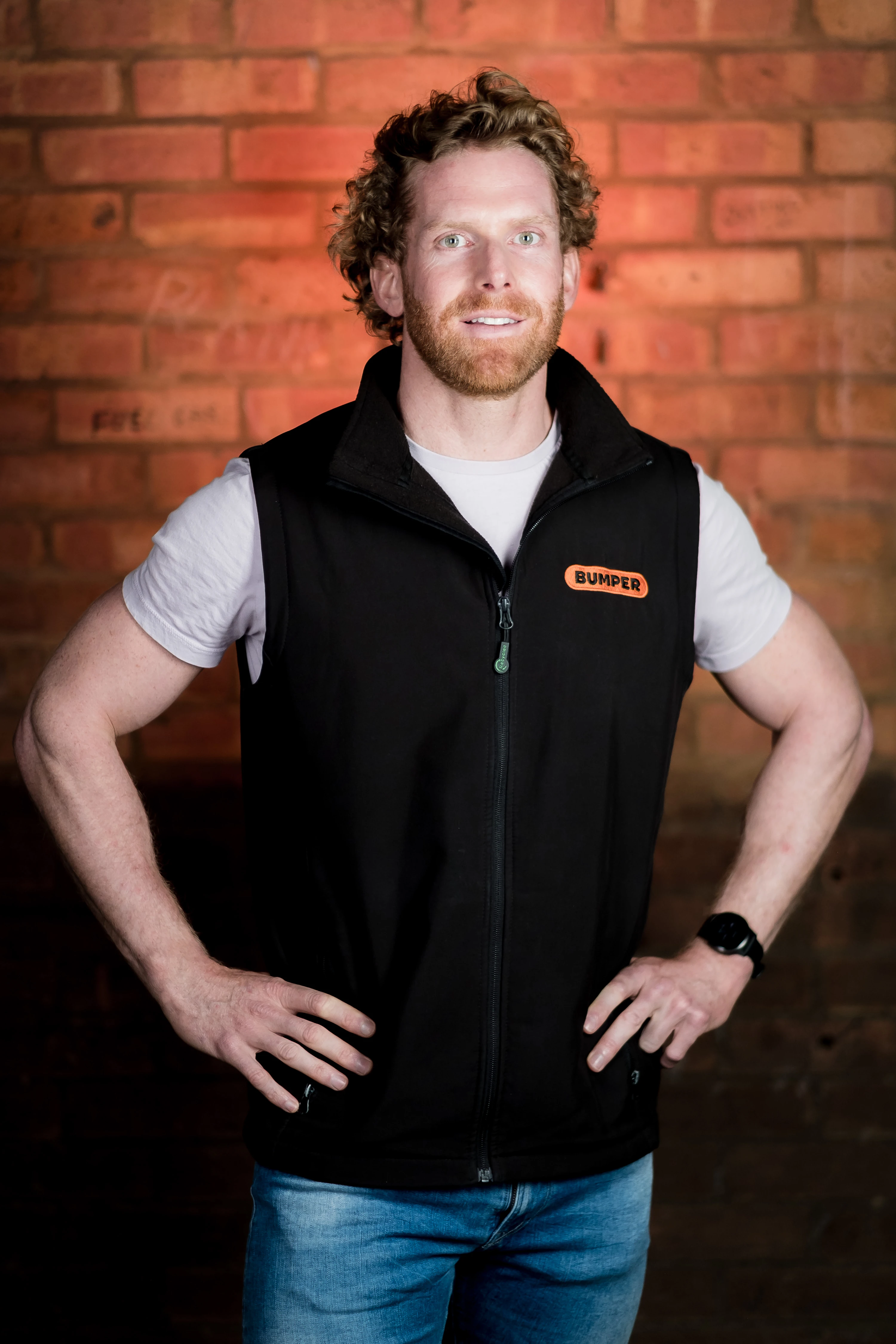 Bumper Team Photography - Three-quarter portrait, branded Bumper gilet, exposed brick backdrop