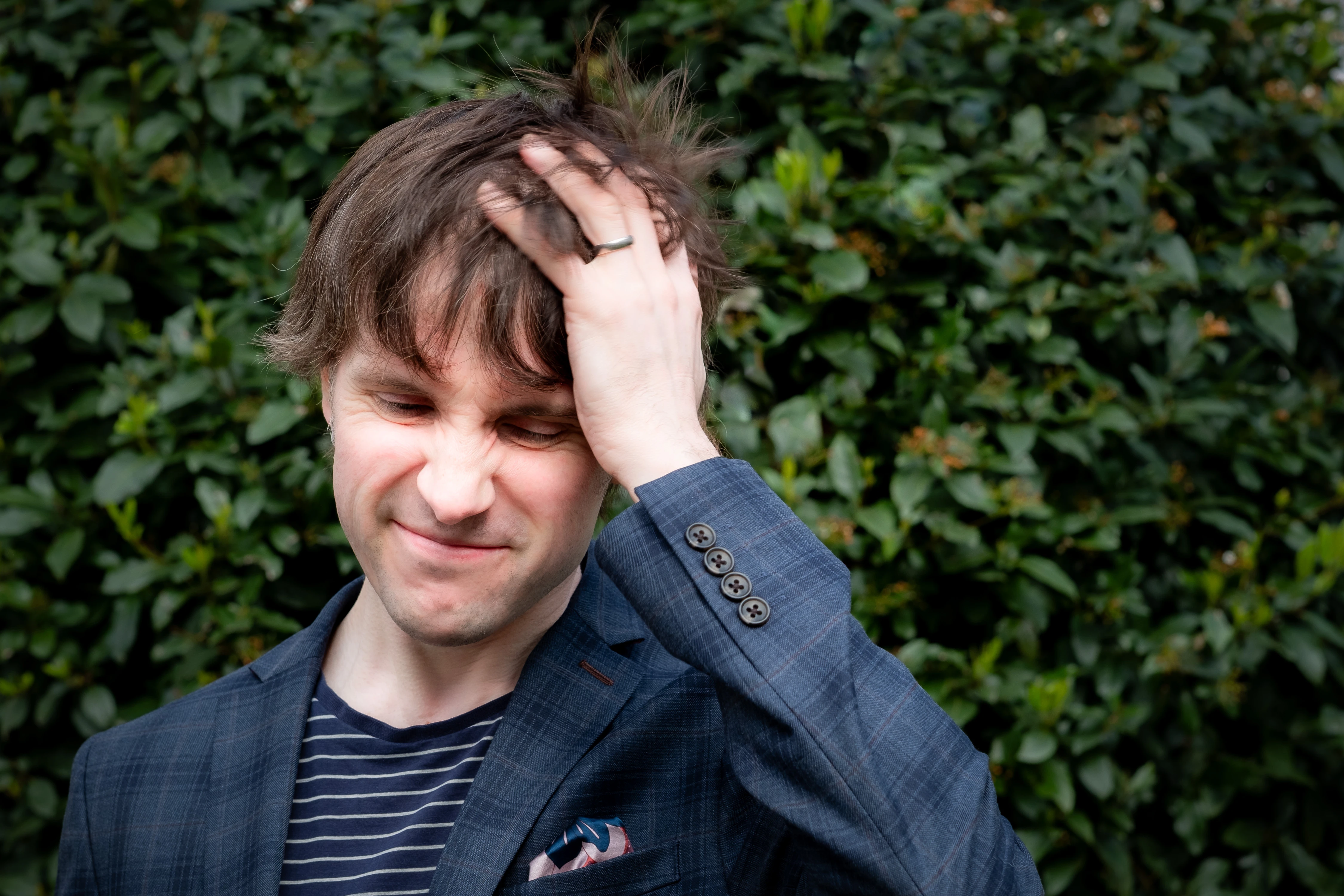 Martin Bryant Personal Branding Headshots - Candid moment against greenery, laughing while pushing hair back