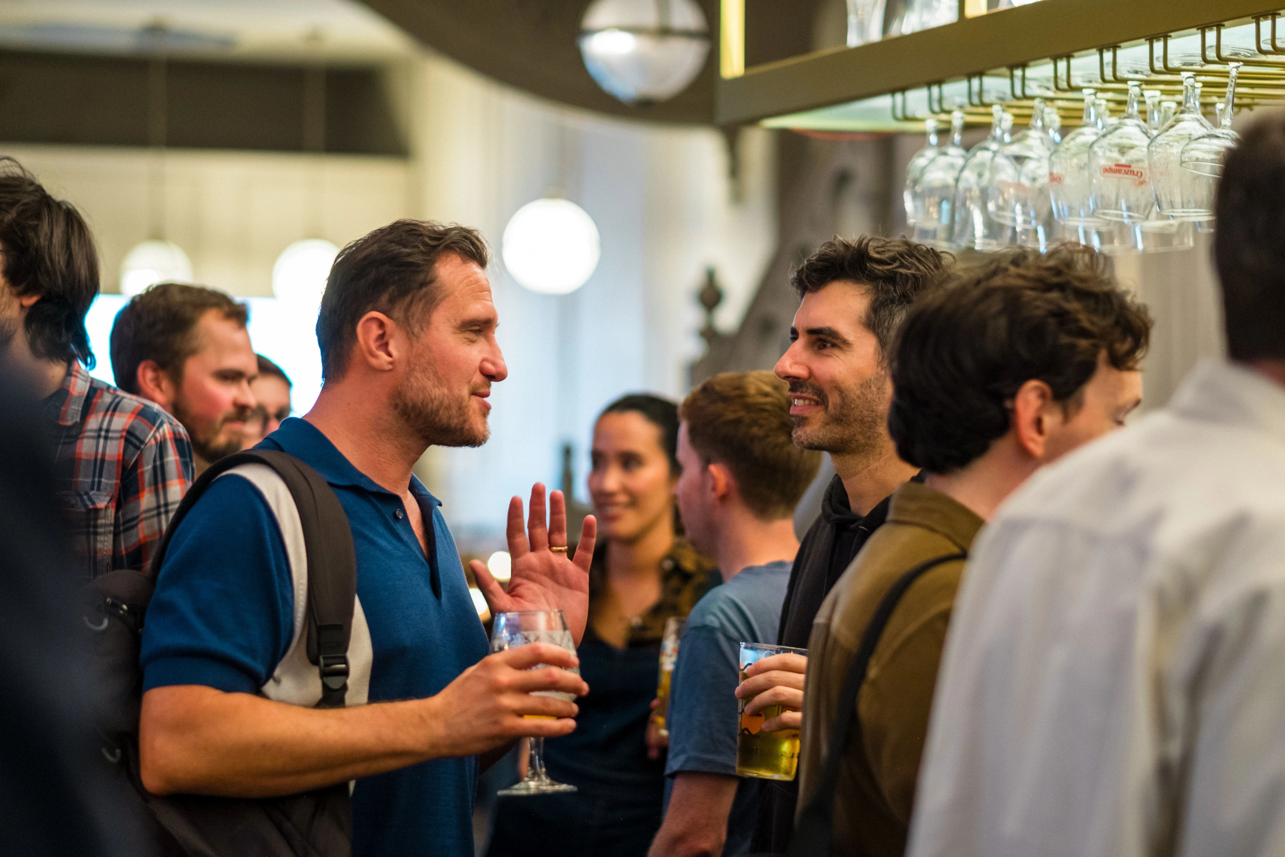 Planet A Ventures Meetup London - Guests in animated conversation under the hanging bar glassware