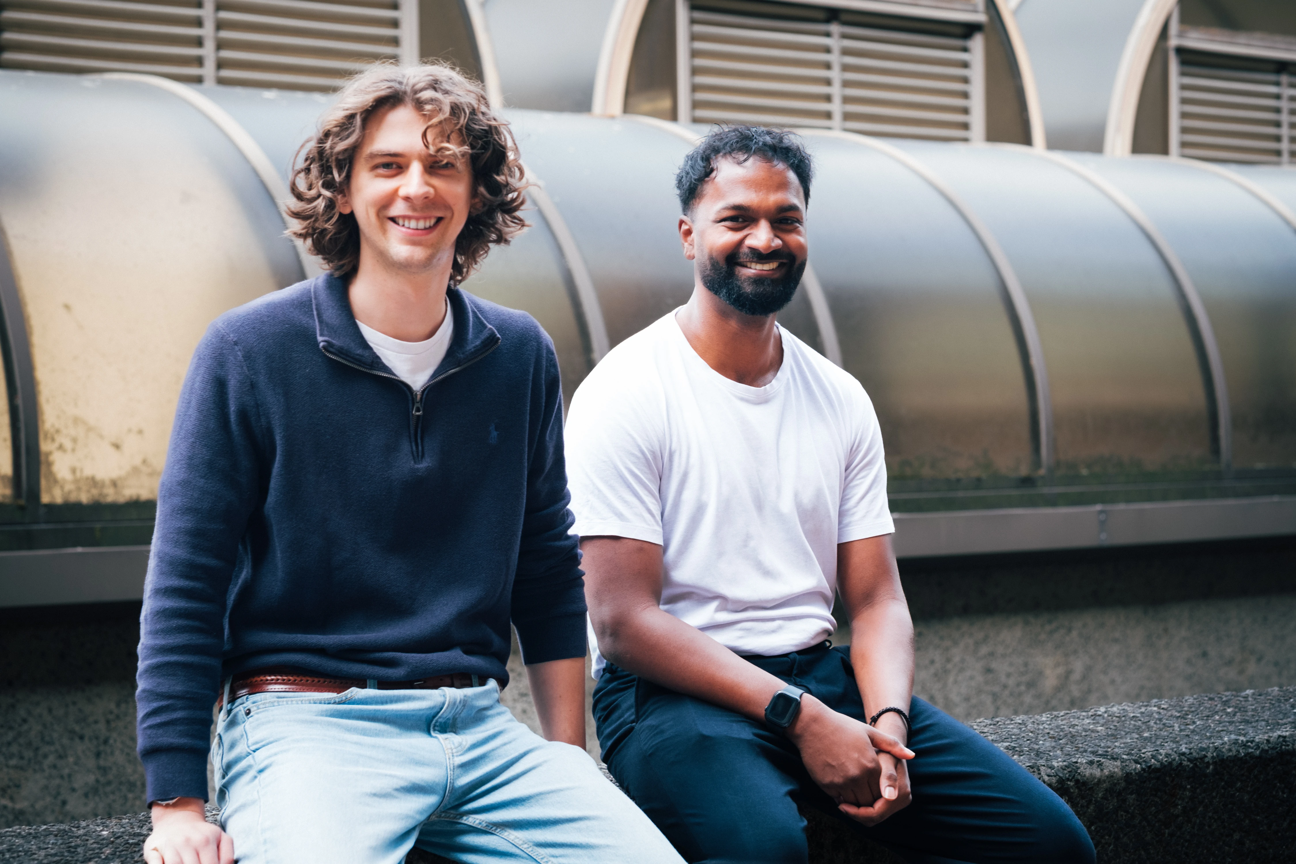 Zenithon AI Founders - Founders seated together on a concrete ledge beneath the curved glass roof